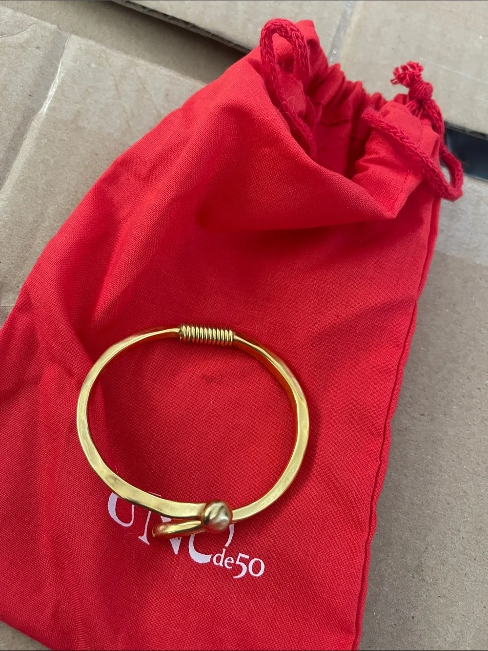 UNO de 50 Gold-Tone Hammered Coil Bypass Bracelet on Red Pouch